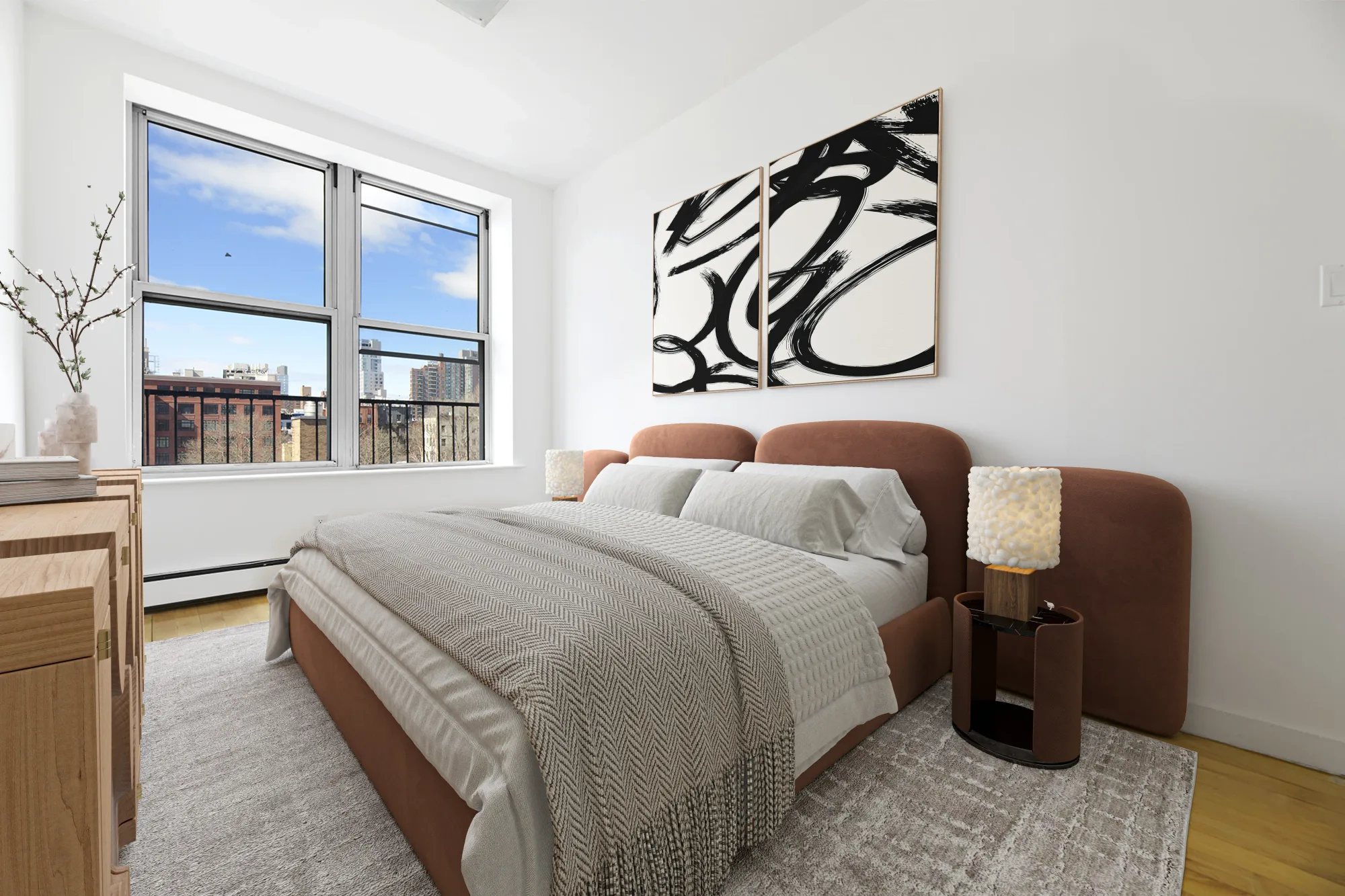 Bedroom with brown bed frame, gray bedding, large window with city view, abstract wall art, and wooden furniture.