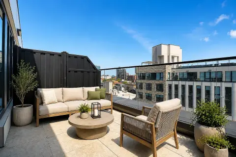 Rooftop terrace with seating area, round fire pit, potted plants, and city views.