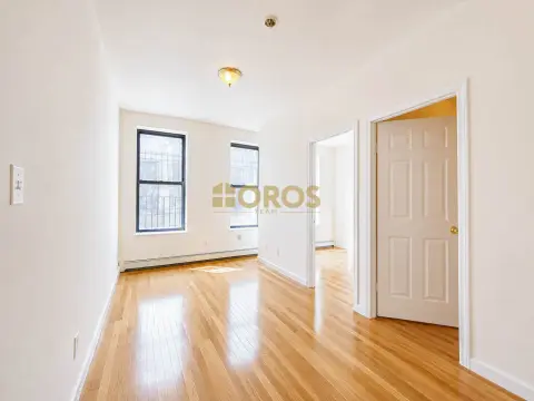 Bright hallway with hardwood floors, white walls, two windows, and white doors leading to other rooms.