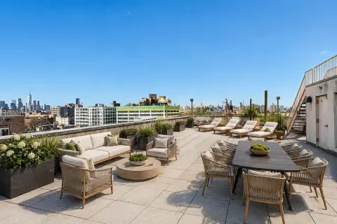 Rooftop terrace with lounge seating, dining table, planters, and city skyline views.