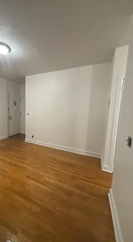 Empty room with hardwood floors, white walls, and a doorway on the right side.