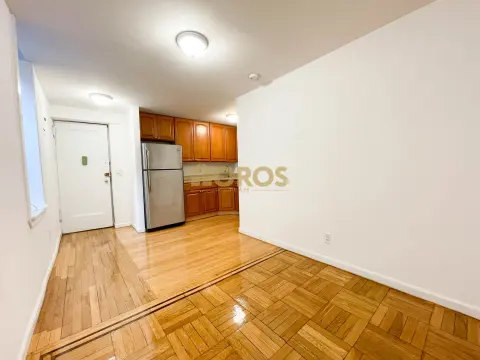 Kitchen and dining area with wooden cabinets, stainless steel appliances, hardwood floors, and white walls.