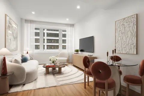 Modern living room with white curved sofa, wooden dining table, TV on stand, large windows overlooking city, and hardwood floors.