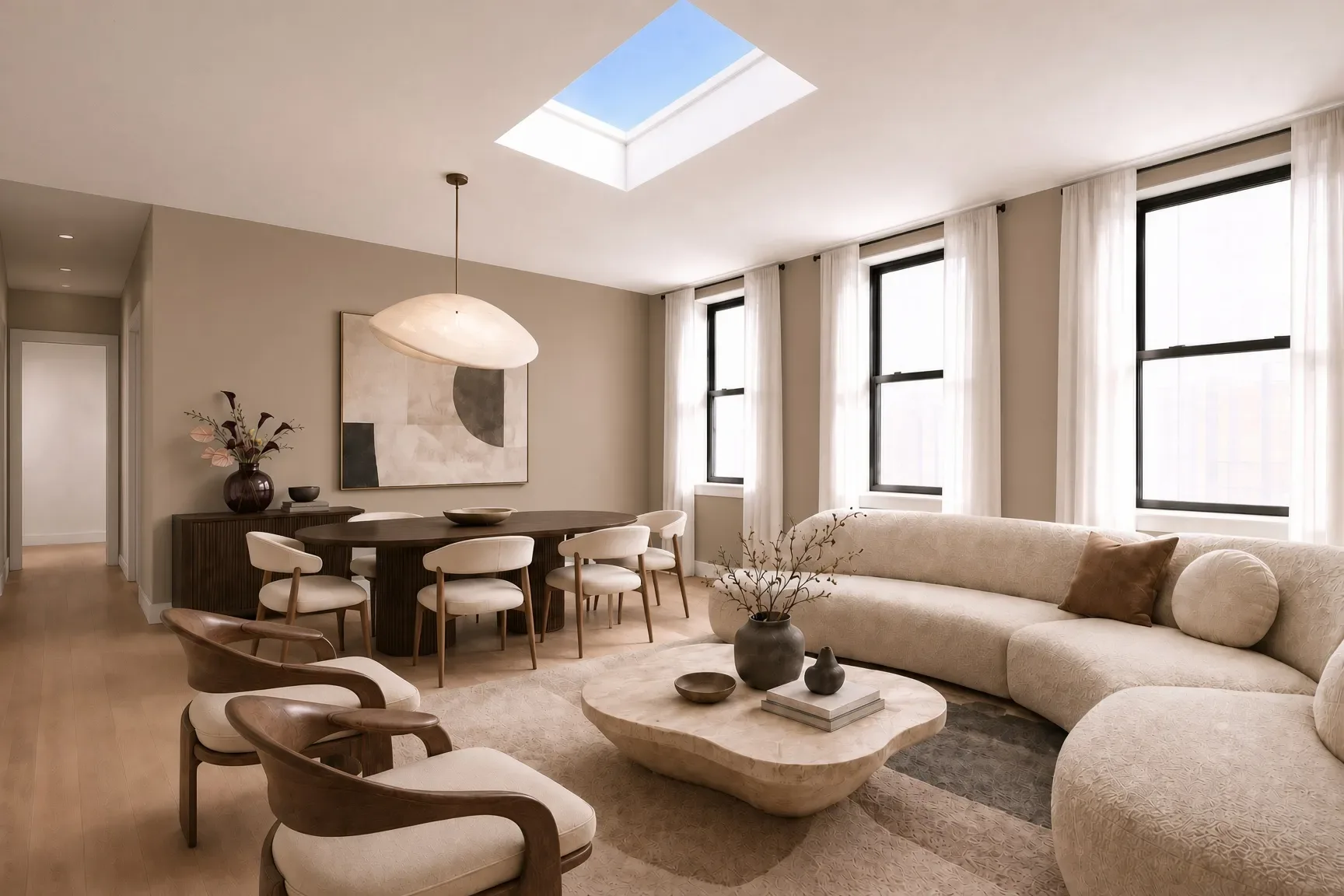 Open-plan living and dining area with beige sofa, dining table, skylight, large windows and hardwood floors.