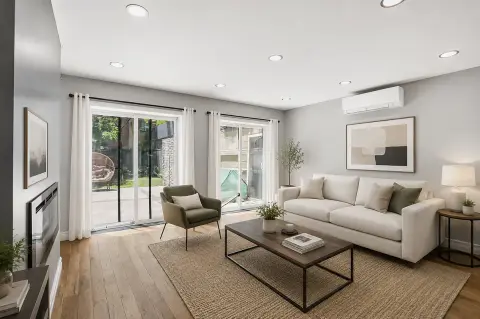 Living room with beige sofa, olive armchair, glass coffee table, fireplace, and sliding glass doors opening to a patio.