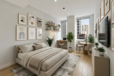 Bedroom with queen bed, framed wall art, desk area, potted plants, and city views through large windows.