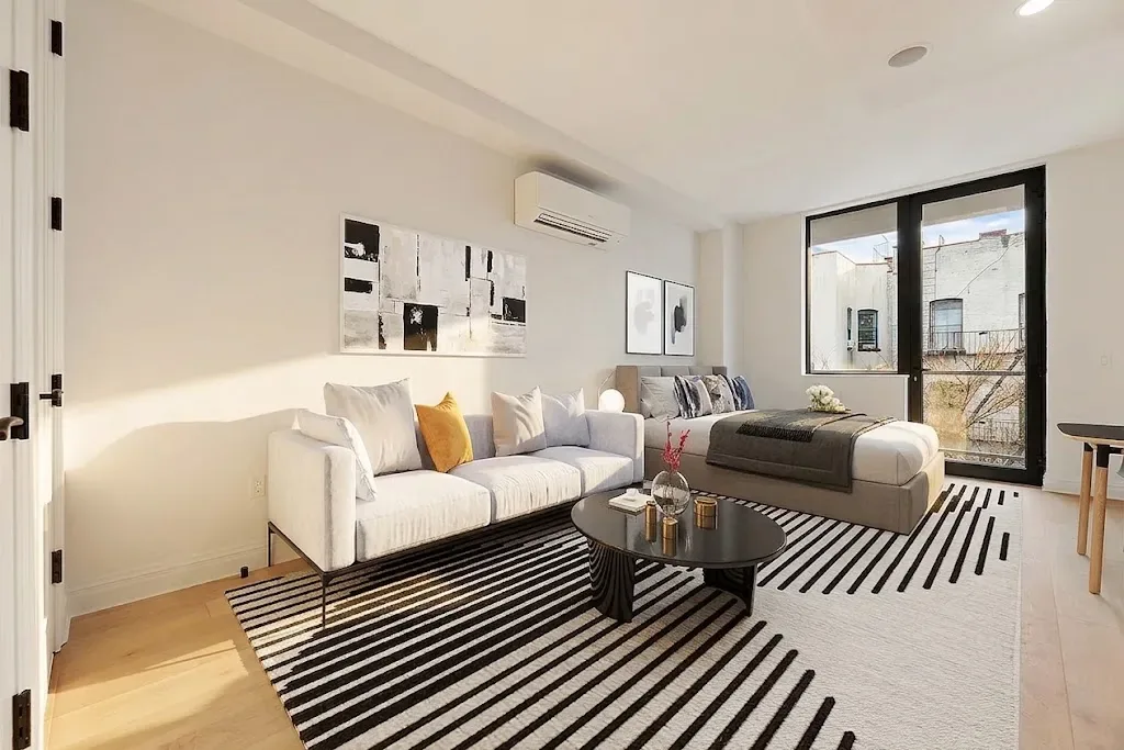 Modern living room with white sofa, striped area rug, glass doors opening to a balcony, and minimalist wall art.