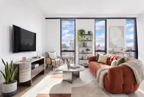 Modern living room with floor-to-ceiling windows, terracotta sofa, TV on wall, and city skyline views.