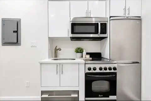 Kitchen with white cabinets, stainless steel appliances, microwave, gas range, and refrigerator.