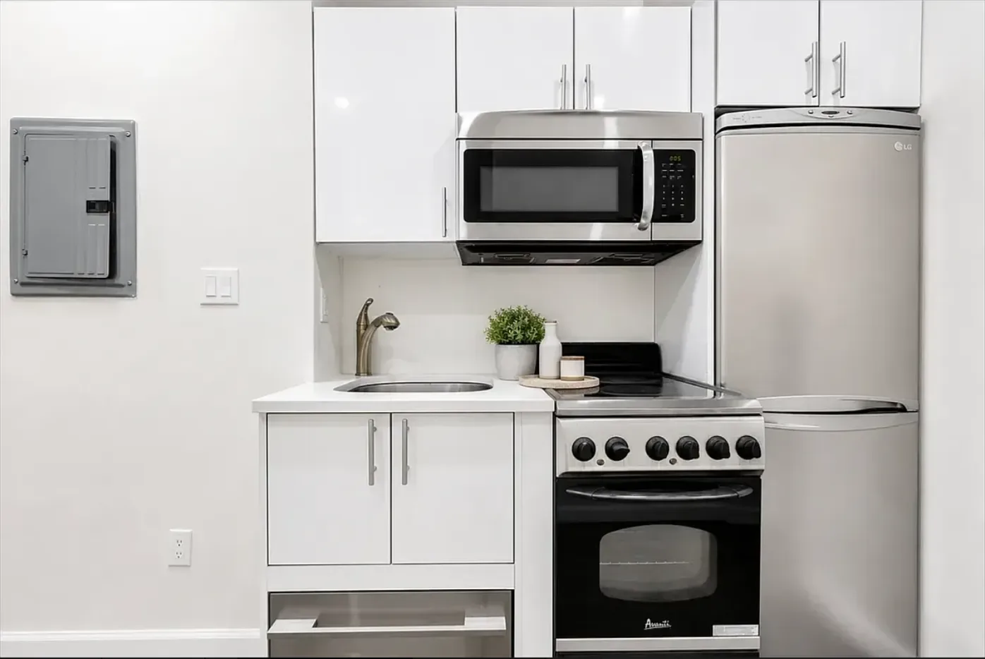 Kitchen with white cabinets, stainless steel appliances, microwave, gas range, and refrigerator.