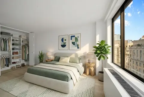 Bedroom with green and white bedding, open wardrobe, potted plants, artwork, and large windows overlooking a city street.