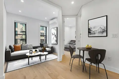 Open-plan living and dining area with hardwood floors, white walls, built-in shelving, sofa, dining table and chairs.