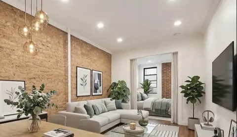Living room with cork accent wall, gray sectional sofa, pendant lights, potted plants, and wall-mounted TV.