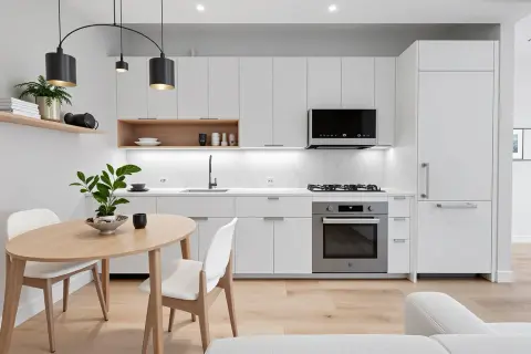 Modern kitchen with white cabinetry, wooden dining table, pendant lights, and stainless steel appliances.