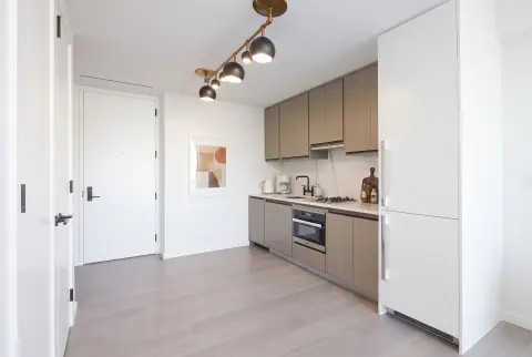 Modern kitchen with taupe cabinetry, white appliances, pendant lighting, and gray tile flooring.