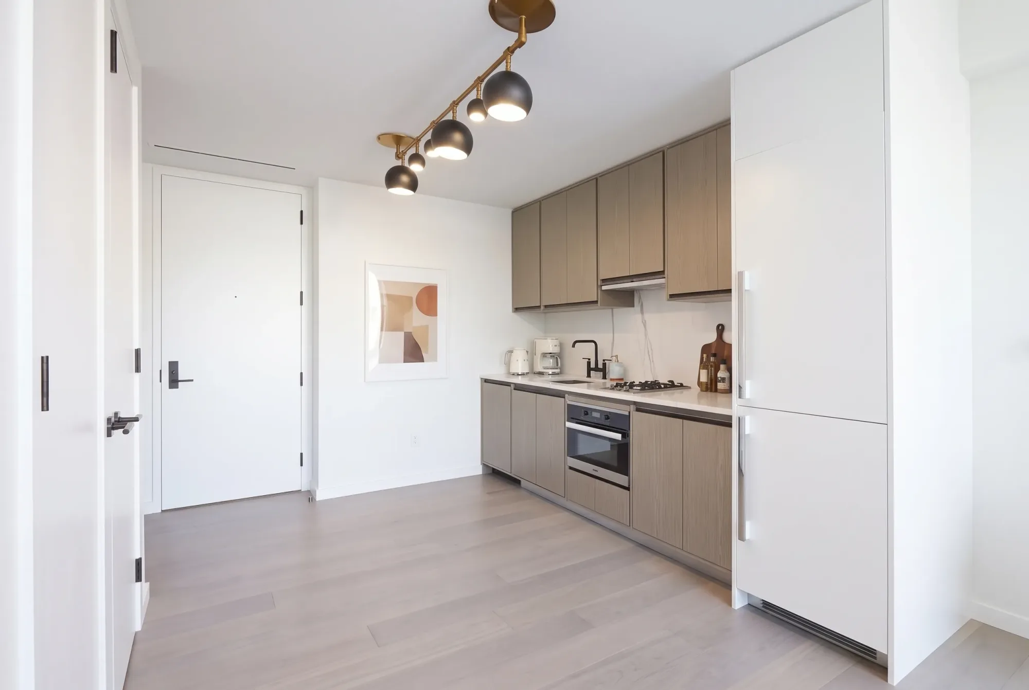 Modern kitchen with taupe cabinetry, white appliances, pendant lighting, and gray tile flooring.